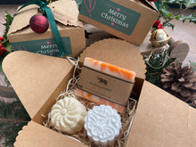 Gift set with natural handmade soap and aromatherapy shower steamers in a decorative box with Christmas-themed elements.