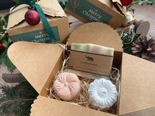 Gift set with natural handmade soap and aromatherapy shower steamers in a decorative box with Christmas-themed elements.