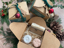 Gift set with natural handmade soap and aromatherapy shower steamers in a decorative box with Christmas-themed elements.