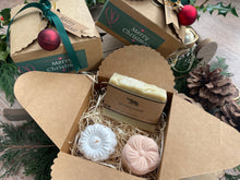Gift set with natural handmade soap and aromatherapy shower steamers in a decorative box with Christmas-themed elements.