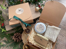 Natural handmade body butter, along with a natural soap bar and exfoliating jute bag in a Christmas gift box with ribbon and gift tag.