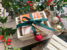 Natural, handmade soap bars in a wooden crate with Christmas ribbon, tag and bauble.