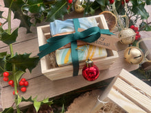 Natural, handmade soap bars in a wooden crate with Christmas ribbon, tag and bauble.